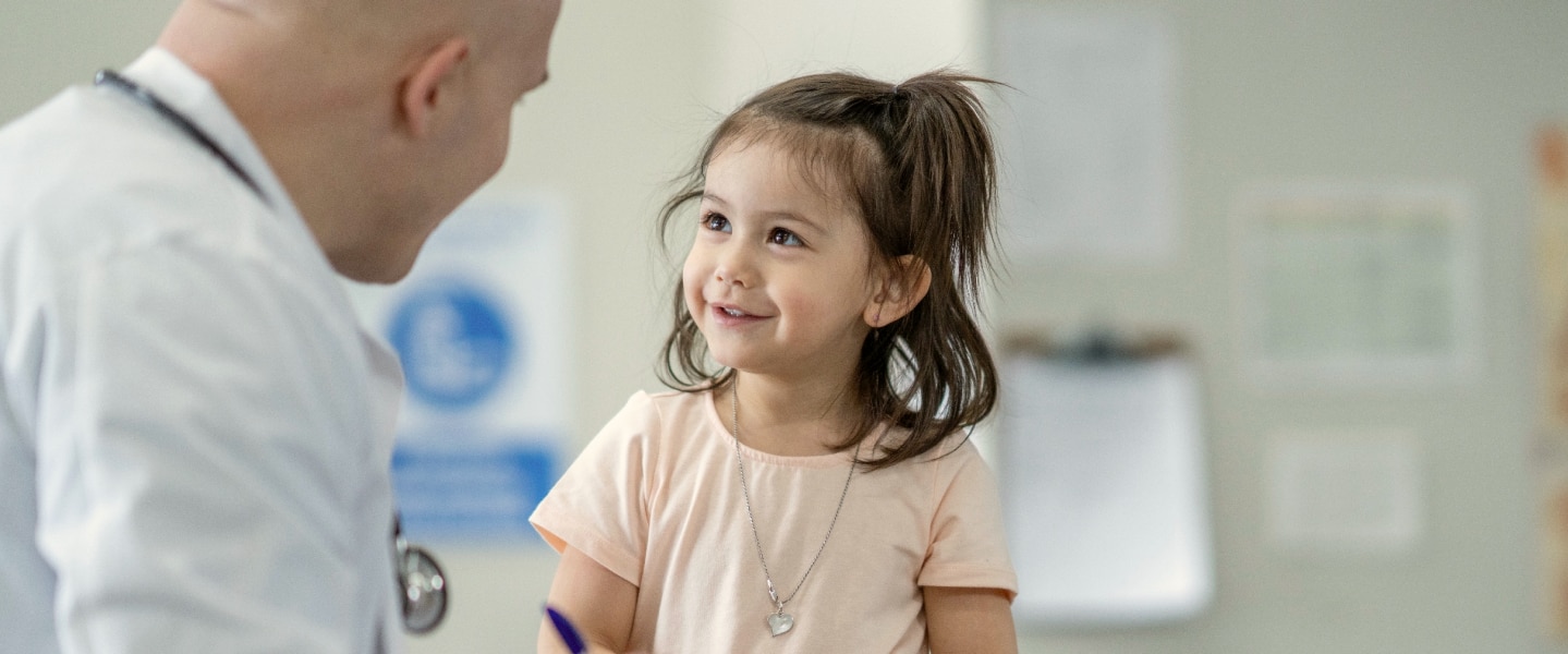 Child smiling at her pediatrician in a medical appointment.