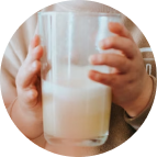 Child's hands holding a glass of hypoallergenic dairy-free formula.